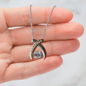 Pode incluir: Um colar de prata com um pingente de ouro e prata com um grande cristal transparente rodeado por cristais menores.