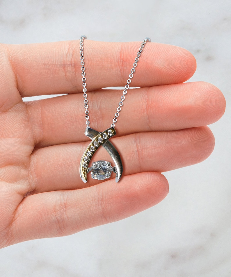 Pode incluir: Um colar de prata com um pingente de ouro e prata com um grande cristal transparente rodeado por cristais menores.