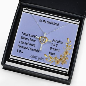 K&ouml;nnte beinhalten: Eine silberne Halskette mit einem goldenen Herz- und Kreuzanh&auml;nger. Die Halskette kommt in einer schwarzen Box mit violettem Hintergrund und dem Text "To My Boyfriend I don't need When I have I do not need Because I already YOU LOVE you Paradise YOU Dreams have".