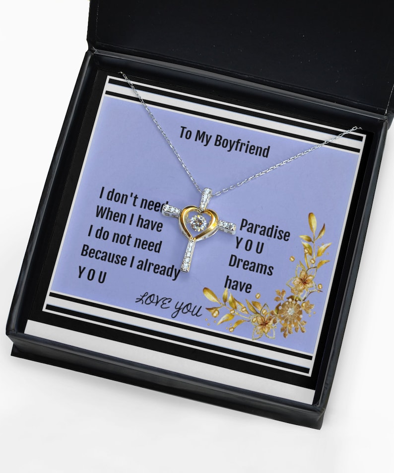 K&ouml;nnte beinhalten: Eine silberne Halskette mit einem goldenen Herz- und Kreuzanh&auml;nger. Die Halskette kommt in einer schwarzen Box mit violettem Hintergrund und dem Text "To My Boyfriend I don't need When I have I do not need Because I already YOU LOVE you Paradise YOU Dreams have".