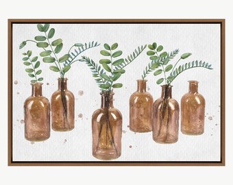 May include: A watercolour painting featuring six brown glass bottles, each containing green leafy branches. The bottles are arranged in a row against a white backdrop with subtle brown paint splatters. The artwork is framed in a brown wooden frame.