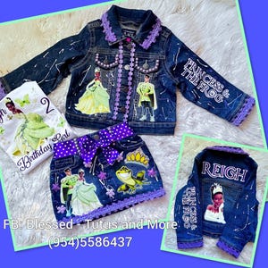 May include: A dark blue denim jacket and skirt set featuring Princess and the Frog graphics, purple lace trim, and pearl accents. The jacket back displays the name REIGH. A white t-shirt with a princess graphic and the text Birthday Girl is included.