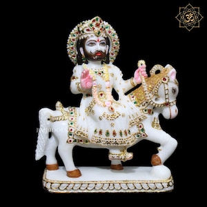 May include: White marble statue of a deity riding a white horse. The deity is wearing a white robe with gold and green embellishments and a crown. The horse is adorned with gold and green decorations.