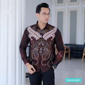 May include: A long-sleeved shirt with a brown background and a white and blue batik pattern. The shirt has a button-down collar and a pocket on the left chest.