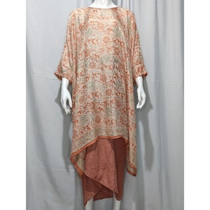 May include: A long, flowing, peach-colored dress with a floral pattern. The dress has a loose, comfortable fit and a high neckline. The dress is made of a soft, lightweight fabric.