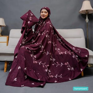 May include: A burgundy prayer garment set with a floral pattern. The set includes a head covering and a long, flowing robe. The floral design features white and light pink leaves and vines. The garment is made of a soft, draping fabric.