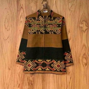 Puede incluir: Una chaqueta de color marrón, negro y rojo con un patrón. La chaqueta está hecha de un tejido tejido con un diseño tradicional.