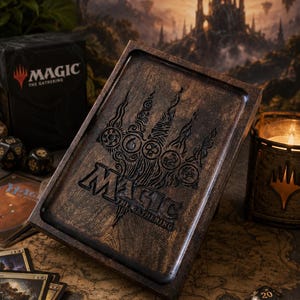 May include: A wooden Magic: The Gathering card box with a carved design of the game's logo and symbols. The box is brown and sits on a map with dice and cards. A black card box and candle are also visible.
