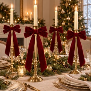 Può includere: Quattro alti candelabri in ottone disposti su un tavolo, ciascuno con una candela bianca. Ogni candelabro è decorato con un grande fiocco in velluto rosso scuro legato attorno allo stelo. La finitura in ottone è lucida e riflettente.