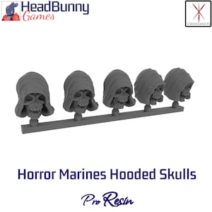 Peut inclure: Rangée de cinq crânes gris en résine, représentant des Horror Marines Hooded Skulls. Chaque crâne est coiffé d'une capuche et monté sur une petite base. Le texte "Horror Marines Hooded Skulls" et "Pro Resin" est imprimé en dessous.