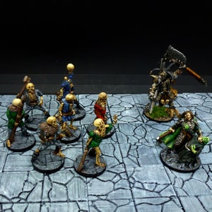 Peut inclure: Une sc&egrave;ne de jeu de table avec des figurines miniatures peintes. Un guerrier squelettique avec une &eacute;p&eacute;e et un bouclier se tient devant un groupe de squelettes. Une figure &agrave; la peau verte avec une &eacute;p&eacute;e et un bouclier se tient &agrave; l'arri&egrave;re-plan. Les figurines sont sur une surface carrel&eacute;e grise et blanche.