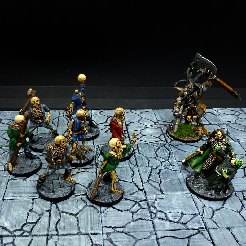 Peut inclure: Une sc&egrave;ne de jeu de table avec des figurines miniatures peintes. Un guerrier squelettique avec une &eacute;p&eacute;e et un bouclier se tient devant un groupe de squelettes. Une figure &agrave; la peau verte avec une &eacute;p&eacute;e et un bouclier se tient &agrave; l'arri&egrave;re-plan. Les figurines sont sur une surface carrel&eacute;e grise et blanche.