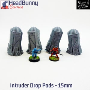 May include: Four gray 15mm scale plastic intruder drop pods, two with open doors, two with closed doors.  The pods are on a white surface.  The text "Intruder Drop Pods - 15mm" is below the pods.