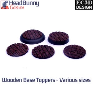 Puede incluir: Cinco cubiertas de base de madera marrón con textura de vetas de madera. Las cubiertas son de varios tamaños y se asientan sobre bases negras. El texto "Wooden Base Toppers - Various sizes" está en la parte inferior. Logos de HeadBunny Games y EC3D Design.