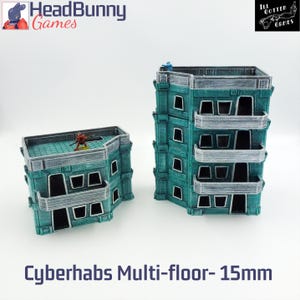 May include: Two teal and grey multi-floor buildings with balconies and windows. The buildings are labelled "Cyberhabs Multi-floor- 15mm". The buildings are for tabletop gaming. The HeadBunny Games and Ill Gotten Games logos are visible.