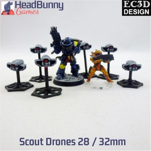 May include: Six gray and black scout drones with red lights on top, standing on hexagonal bases. The drones are 28/32mm in size.  A blue and yellow space marine and a smaller orange space marine stand behind the drones.
