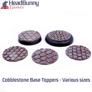 Pode incluir: Toppers de base de calçada em vários tamanhos. Os toppers apresentam um design de calçada texturizado em tons de castanho e cinza. Os toppers são redondos e assentam sobre uma base preta. O logótipo HeadBunny Games está no canto superior esquerdo.