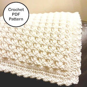 May include: Cream-colored crochet blanket with a textured pattern and scalloped edge. The blanket is folded, showing the detailed stitch work. A circular graphic with the text "Crochet PDF Pattern" is in the upper left corner.