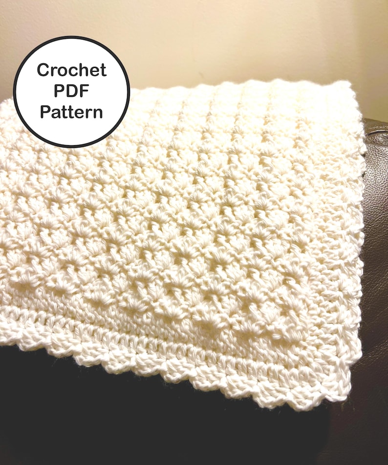 May include: Cream-colored crochet blanket with a textured pattern and scalloped edge. The blanket is folded, showing the detailed stitch work. A circular graphic with the text "Crochet PDF Pattern" is in the upper left corner.