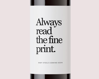 May include: A bottle of red wine with a white label that says "Always read the fine print."  The label also says "Baby Steele Coming Soon".