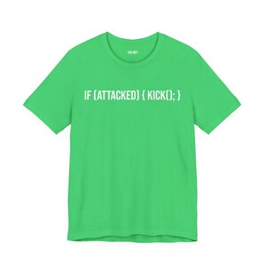 May include: A bright green short-sleeved t-shirt featuring the white printed text IF (ATTACKED) { KICK(); } across the chest. The shirt has a crew neckline and includes the small white text TKD WIT printed inside the collar area.