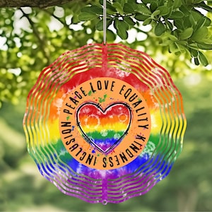 May include: A rainbow-colored metal wind spinner with a heart in the center. The heart is surrounded by a circle with the words "Inclusion Peace Love Equality Kindness" written around it.