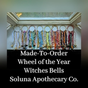 Puede incluir: Un conjunto colorido de campanas de bruja 'Rueda del Año' hechas a mano con campanas doradas y cintas. Las campanas cuelgan de una ventana. El texto 'Made-To-Order Wheel of the Year Witches Bells Soluna Apothecary Co.' se muestra debajo de las campanas.