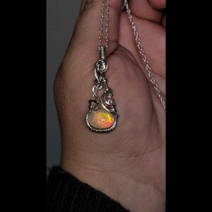 2.3 carat Ethiopian Fire Opal wire wrapped in luxurious 940 Argentium Silver, known for its superior brightness and tarnish resistance, into a high-end gemstone pendant necklace that exudes a whimsical earthy charm reminiscent of vintage treasures.