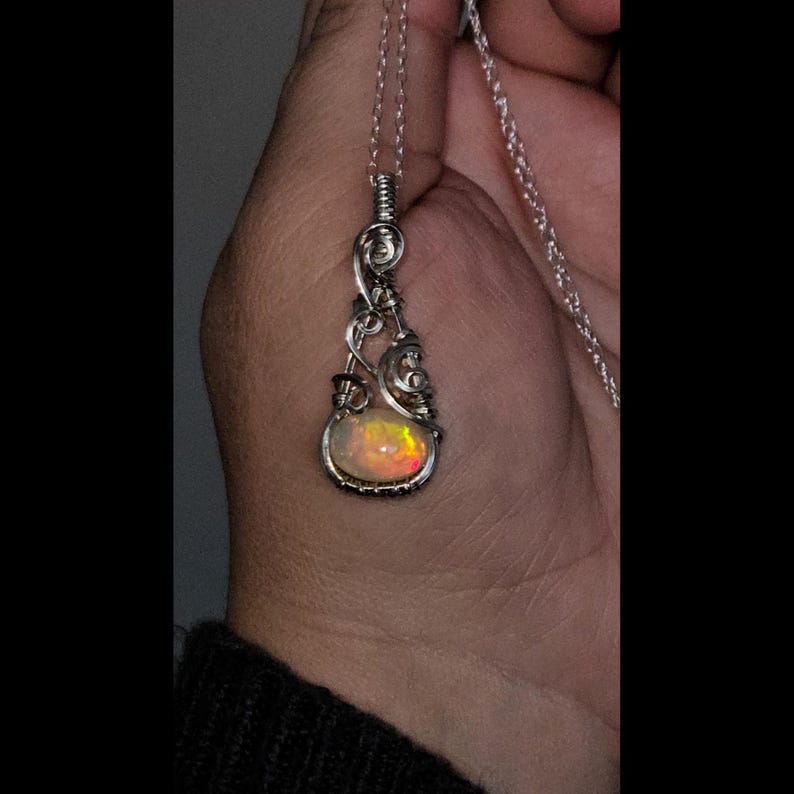2.3 carat Ethiopian Fire Opal wire wrapped in luxurious 940 Argentium Silver, known for its superior brightness and tarnish resistance, into a high-end gemstone pendant necklace that exudes a whimsical earthy charm reminiscent of vintage treasures.