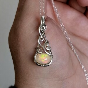 May include: A silver chain necklace with a pendant featuring a white opal gemstone wrapped in silver wire.