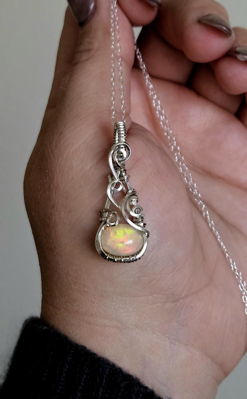 May include: A silver chain necklace with a pendant featuring a white opal gemstone wrapped in silver wire.