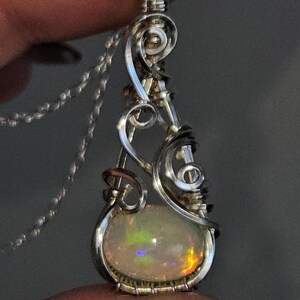 2.3 carat Ethiopian Fire Opal wire wrapped in luxurious 940 Argentium Silver, known for its superior brightness and tarnish resistance, into a high-end gemstone pendant necklace that exudes a whimsical earthy charm reminiscent of vintage treasures.