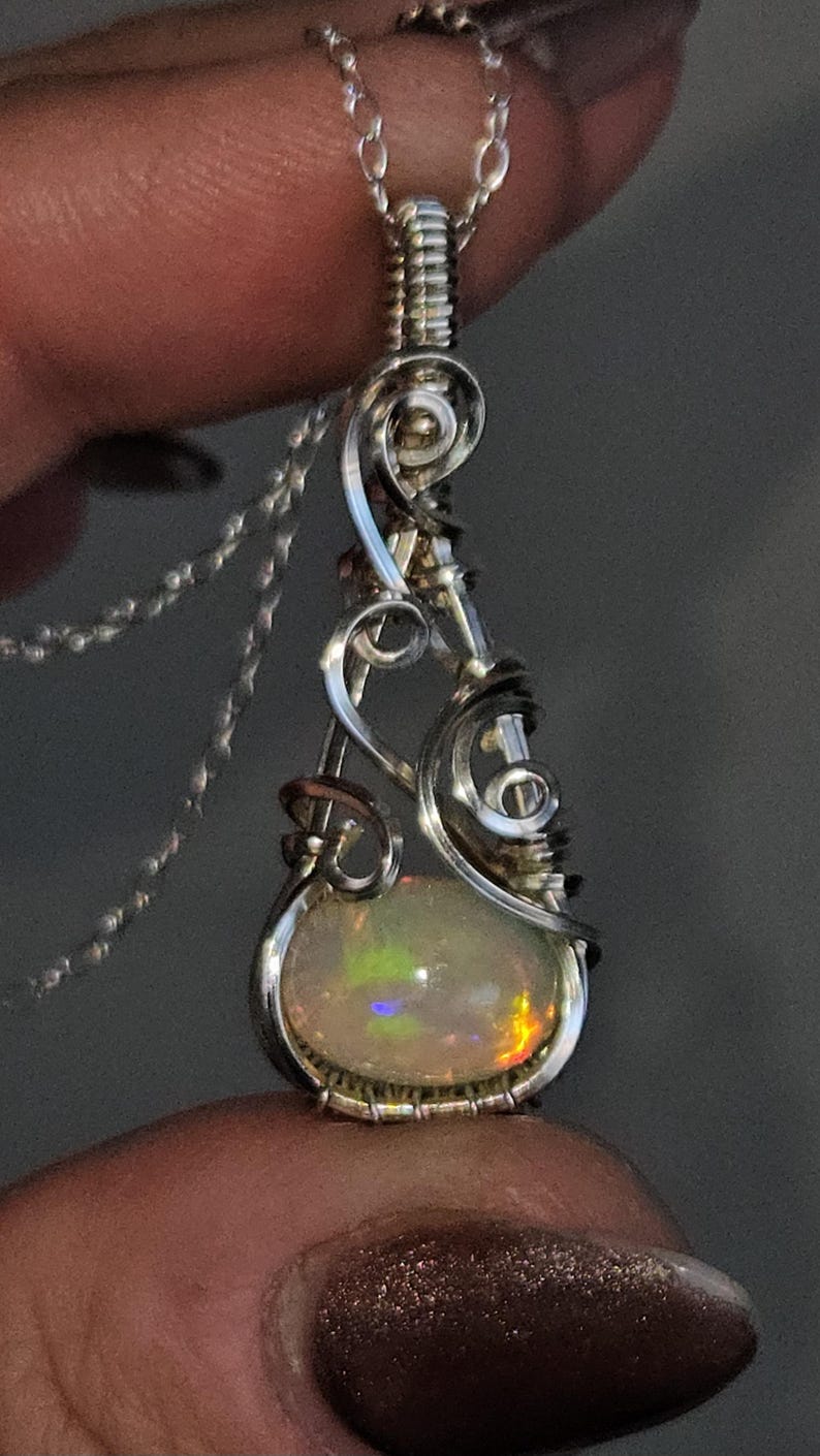 2.3 carat Ethiopian Fire Opal wire wrapped in luxurious 940 Argentium Silver, known for its superior brightness and tarnish resistance, into a high-end gemstone pendant necklace that exudes a whimsical earthy charm reminiscent of vintage treasures.