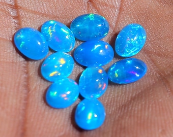 May include: A collection of ten oval-shaped blue opals with iridescent flashes of color.