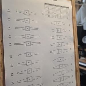 Puede incluir: Una hoja impresa titulada "Groombridge Opals Templates" con diagramas y medidas en milímetros. Los diagramas muestran varias formas con un cuadrado central etiquetado como "10". La hoja está montada sobre una tabla de madera.