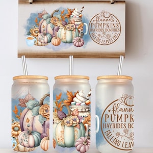 Op de afbeelding: Drie glazen bekers met bamboe deksels en metalen rietjes, met herfstthema-ontwerpen. De ontwerpen omvatten pompoenen, herfstbladeren en de tekst "Flann's Pumpkins". Een houten bord met een vergelijkbaar ontwerp hangt erboven.