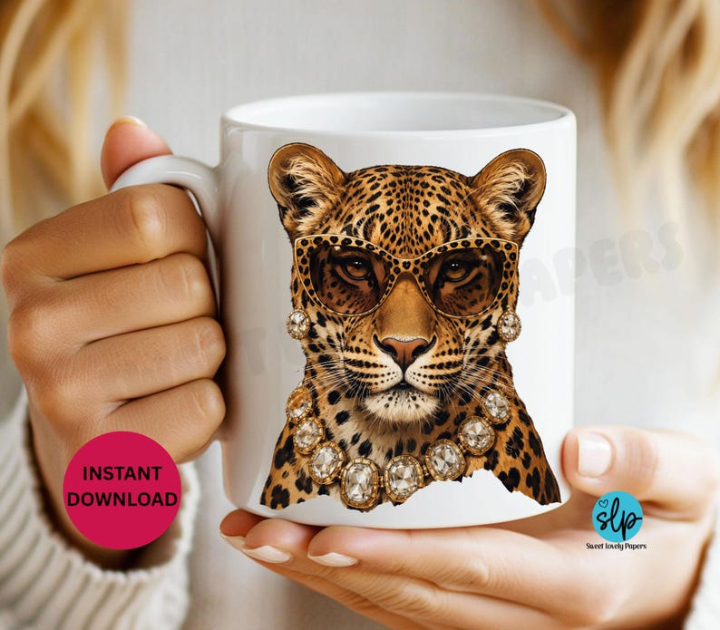 May include: White ceramic mug featuring a leopard wearing sunglasses and a jeweled necklace. The leopard has a spotted coat and is centered on the mug. The mug is held by a person.