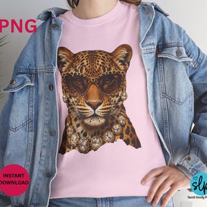 May include: Pink t-shirt featuring a leopard wearing sunglasses and a diamond necklace. The leopard has a spotted coat and is wearing brown-tinted sunglasses. The shirt also has the text "PNG" and "INSTANT DOWNLOAD".