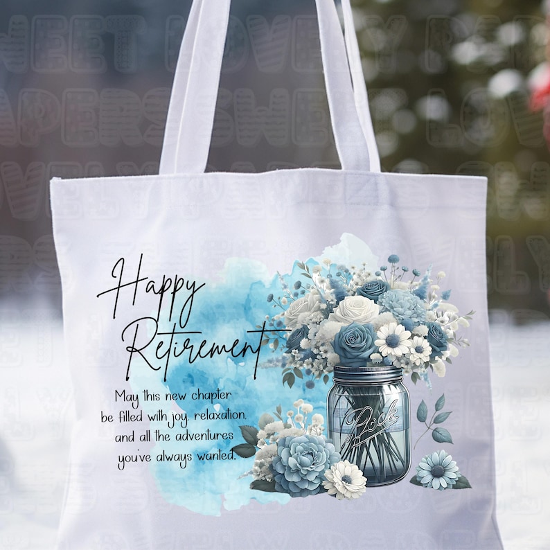 May include: White tote bag with a blue watercolor background and a mason jar filled with blue and white flowers. The text "Happy Retirement" is written in black cursive script. The text "May this new chapter be filled with joy relaxation and all the adventures you've always wanted." is written in black below the flowers.