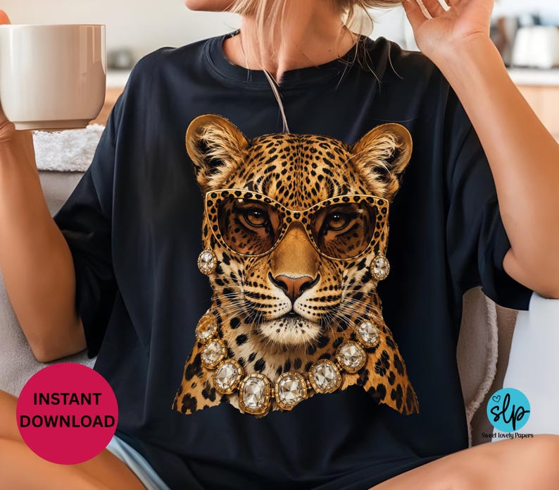 May include: Black t-shirt featuring a leopard wearing sunglasses and a jeweled necklace. The leopard has a spotted coat and is wearing gold-rimmed sunglasses and a necklace with large, clear gemstones. The shirt has a round neck.