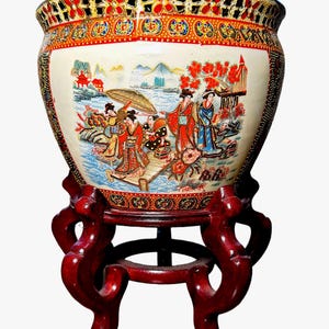 May include: A decorative ceramic planter with a hand-painted Asian scene, set on a dark red wooden stand. The planter features a cream-colored background with a detailed illustration of figures in traditional attire, with red, blue, and gold accents.