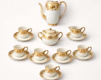May include: A complete antique tea set with a white and gold floral design. The set includes a teapot, sugar bowl, creamer, and six cups with saucers. The gold detailing is prominent on each piece, creating an elegant aesthetic.