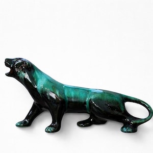 May include: A ceramic panther figurine in a glossy finish. The sculpture features a dark green and black color scheme with a roaring pose. The figurine is a decorative item.