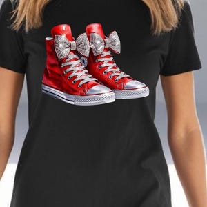 May include: A black t-shirt with a graphic of red high-top sneakers with a large sparkly bow on each shoe.