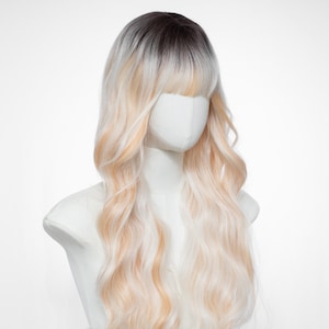 Peluca larga ondulada con flequillo: de raíces oscuras a rubio platino y champán ombré, cabello sintético con degradado natural. Incluye gorro de peluca.