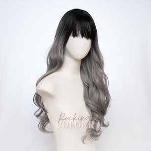May include: A long wavy wig featuring a dark black root color that transitions into a light silver-gray shade. The wig includes straight-cut bangs across the forehead and is displayed on a mannequin head with the text Rocking Colour printed.