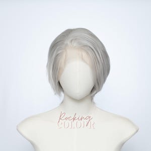 May include: A short, silver-gray wig with a lace front is displayed on a mannequin. The wig has a blunt cut and a natural-looking hairline. The mannequin is on a white background. The text "Rocking COLOR" is visible on the mannequin.
