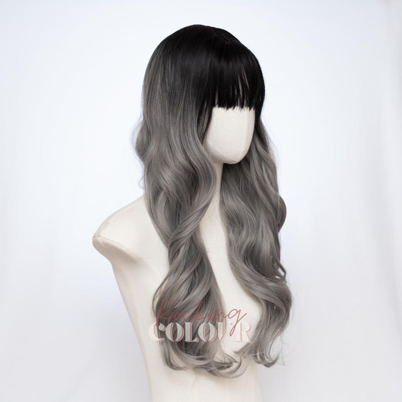 May include: A long, wavy wig featuring a dark black root color that transitions into a light silver-gray shade. The wig includes straight-cut bangs across the forehead and is displayed on a mannequin head. The text "KISSING COLOUR" is visible.