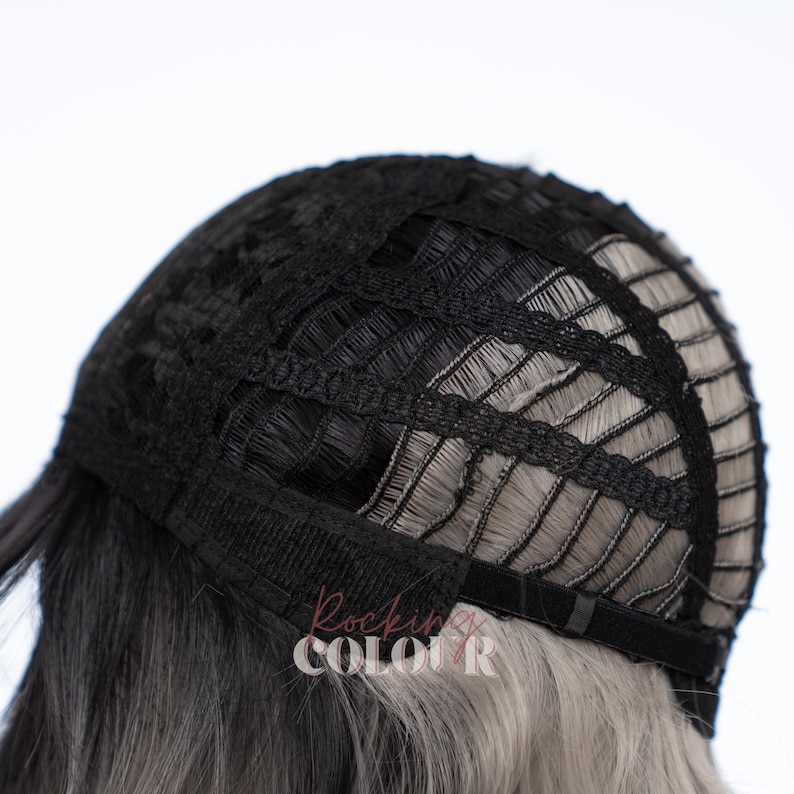 May include: The interior of a wig cap featuring a black mesh construction with horizontal and vertical fabric strips. The cap includes adjustable black elastic straps at the nape area. The text Rockin Colour is visible in a light pink font on the hair.