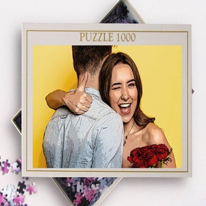 May include: A 1000 piece jigsaw puzzle featuring a couple embracing. The woman is smiling and holding a bouquet of red roses. The background is a bright yellow.